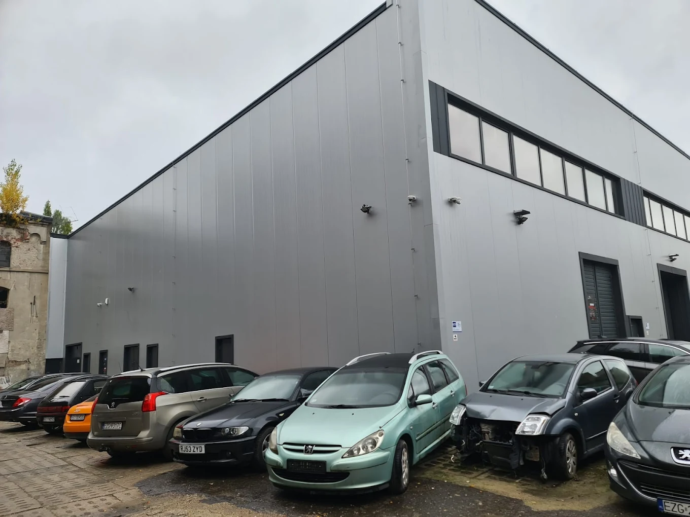 Zewnętrzna część budynku AutoKlinika Serwis Samochodowy w Łodzi przy ulicy Przybyszewskiego 91 – parking przed warsztatem